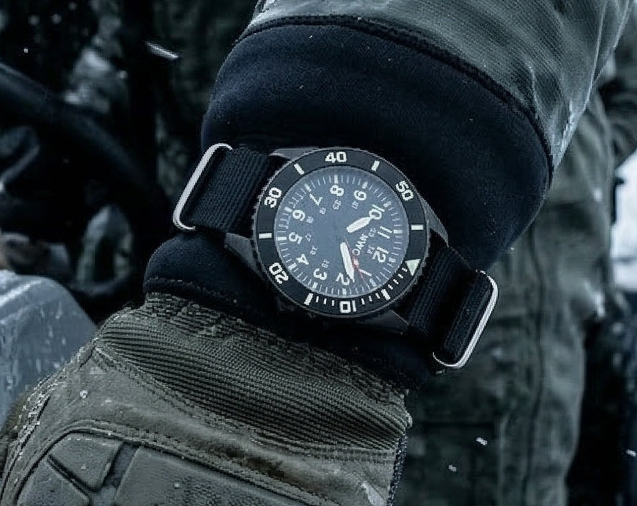 Black wristwatch with a detailed face on a gloved wrist, with a blurred background